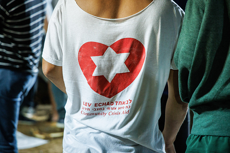 Ein freiwilliger Totengräber trägt T-Shirt mit der Aufschrift 'Lev echad' (dt. ein Herz) und darüber ein Herz mit einem Davidstern, auf dem nationalen Militärfriedhof auf dem Herzlberg in Jerusalem (Israel) am 11. Oktober 2023.