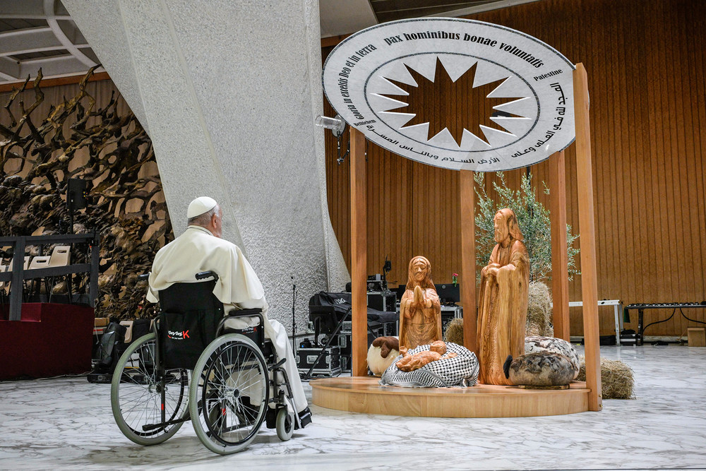 Papst Franziskus vor Krippe in der Audienzhalle / Copyright 2024, KNA GmbH, www.kna.de, All Rights Reserved, Vatican Media Papst Franziskus betet vor der Krippe am 7. Dezember 2024 in der Audienzhalle im Vatikan. Das Jesuskind liegt auf einem schwarz-weißen Palästinensertuch.