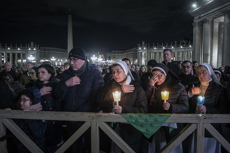 Menschen hinter einer Absperrung darunter Ordensschwestern mit Kerzen, bei einer Rosenkranzandacht für den erkrankten Papst am 28. Februar 2025 auf dem Petersplatz im Vatikan.