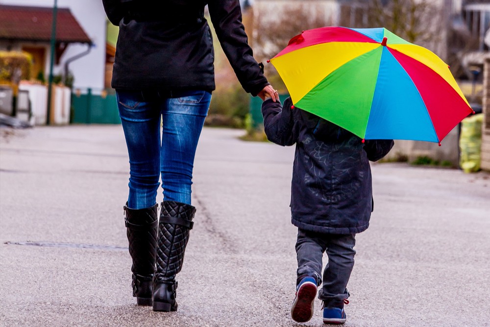 Mutter und Kind mit Regenschirm, Symbol für Solidarität, Hilfe, Hilfspaket, Rettungsschirm